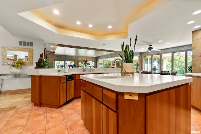 kitchen with kitchen peninsula, ceiling fan, a kitchen island with sink, and sink