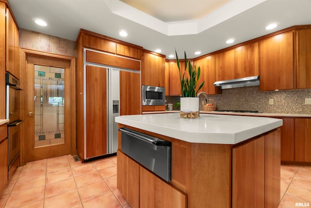 kitchen with built in appliances, a kitchen island, decorative backsplash, light tile patterned floors, and extractor fan