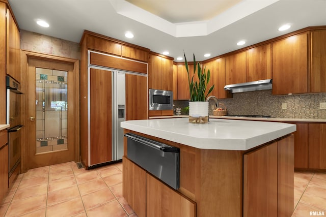 200 W Ravinwoods Rd, Peoria, IL 61615 - kitchen with under cabinet range hood, built in appliances, a warming drawer, brown cabinetry, and recessed lighting