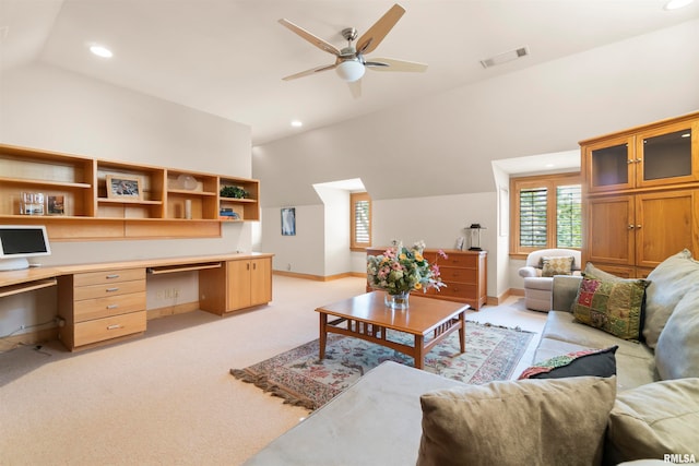 carpeted living room with built in desk, vaulted ceiling, and ceiling fan