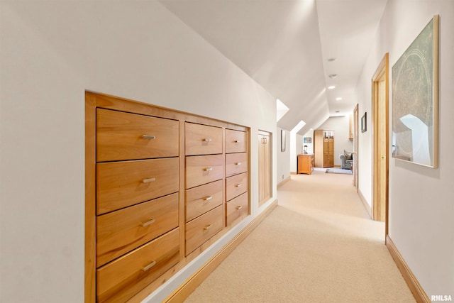 corridor with lofted ceiling and light carpet