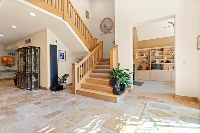 stairway with built in shelves and a towering ceiling