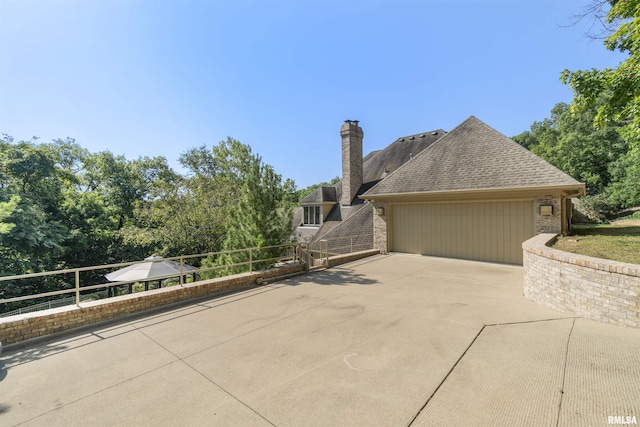 200 W Ravinwoods Rd, Peoria, IL 61615 - view of home's exterior featuring concrete driveway, an attached garage, a chimney, a shingled roof, and brick siding