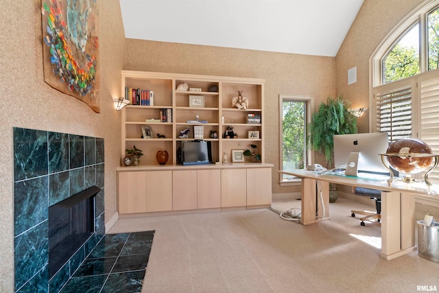 office area featuring carpet floors, a tiled fireplace, and vaulted ceiling