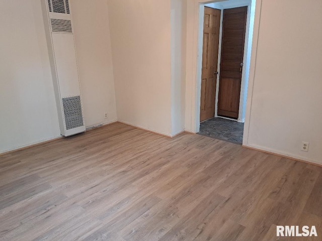 empty room featuring a heating unit, baseboards, and wood finished floors