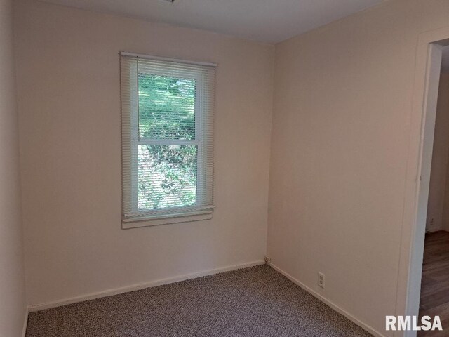 spare room with baseboards and carpet floors