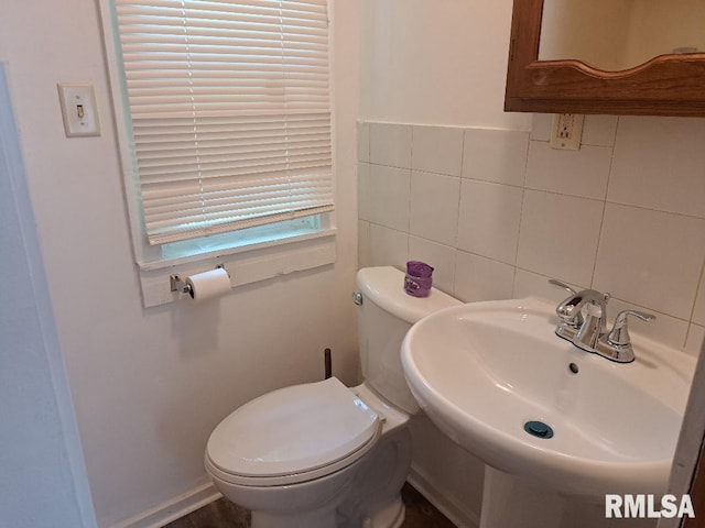 bathroom with a sink, toilet, and tile walls