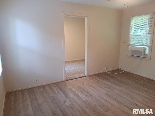 empty room with a ceiling fan, cooling unit, wood finished floors, and baseboards