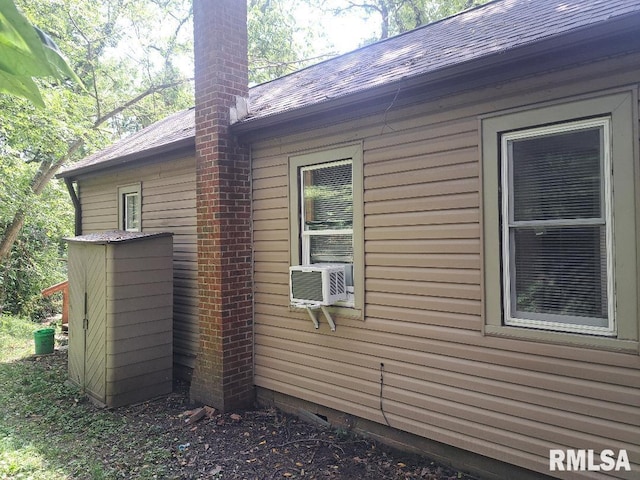 view of property exterior featuring cooling unit, roof with shingles, and a chimney