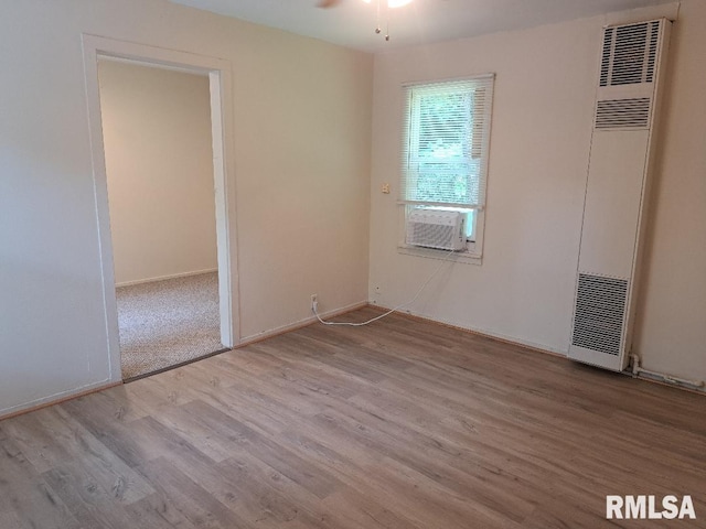 unfurnished bedroom featuring baseboards, wood finished floors, and a heating unit