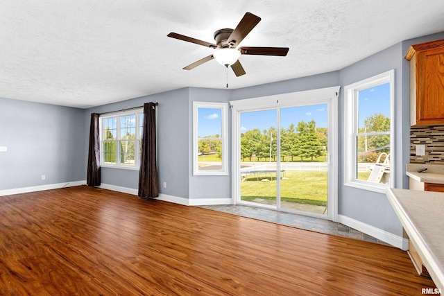 unfurnished living room with ceiling fan, a textured ceiling, and hardwood / wood-style floors