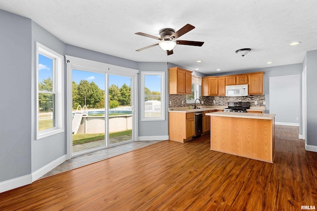 kitchen featuring appliances with stainless steel finishes, dark hardwood / wood-style flooring, tasteful backsplash, and a kitchen island