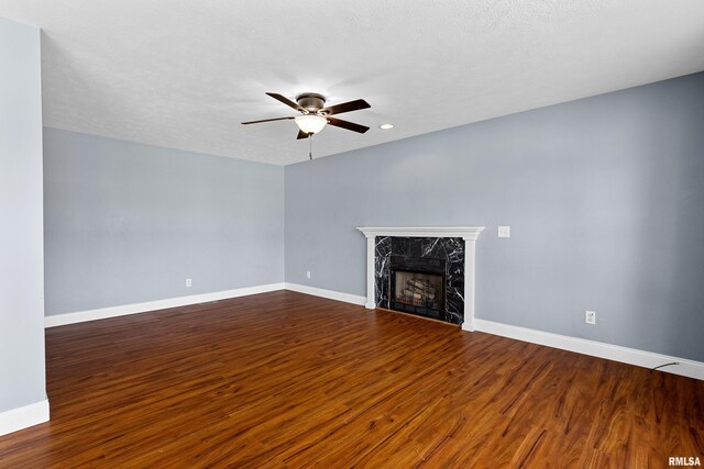 unfurnished living room with ceiling fan, dark wood-type flooring, and a premium fireplace