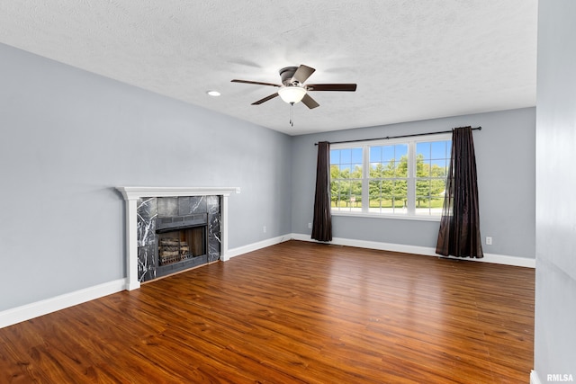 unfurnished living room with ceiling fan, a textured ceiling, dark hardwood / wood-style floors, and a high end fireplace