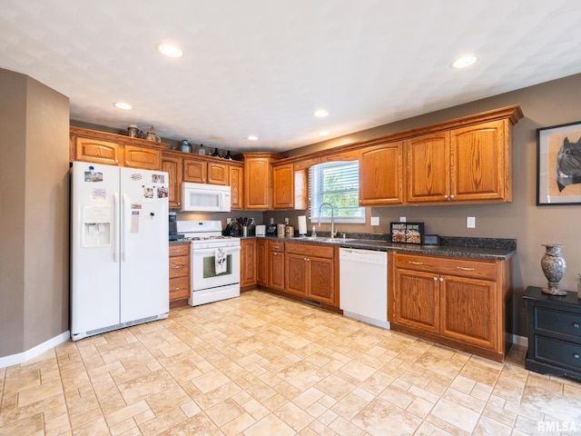 kitchen featuring dark stone counters, white appliances, and sink