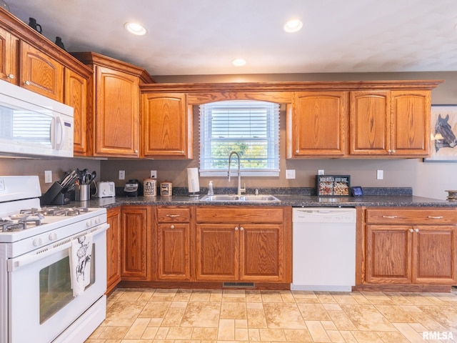 kitchen with sink, white appliances, and dark stone counters