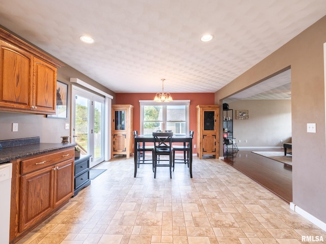 kitchen with white dishwasher, dark stone counters, decorative light fixtures, and a chandelier