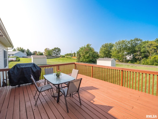 wooden terrace featuring area for grilling, a lawn, and a storage shed