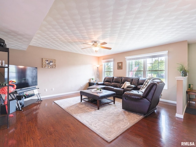 living room featuring dark wood-type flooring, a textured ceiling, and ceiling fan