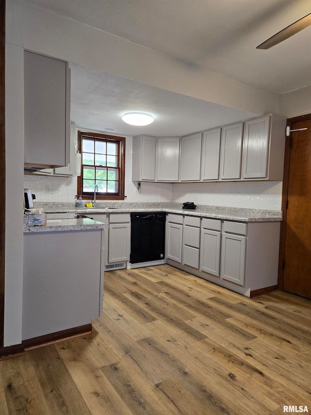 kitchen featuring light stone countertops, decorative backsplash, black dishwasher, gray cabinetry, and light hardwood / wood-style floors