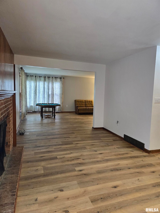 unfurnished living room featuring light hardwood / wood-style flooring, pool table, and a fireplace