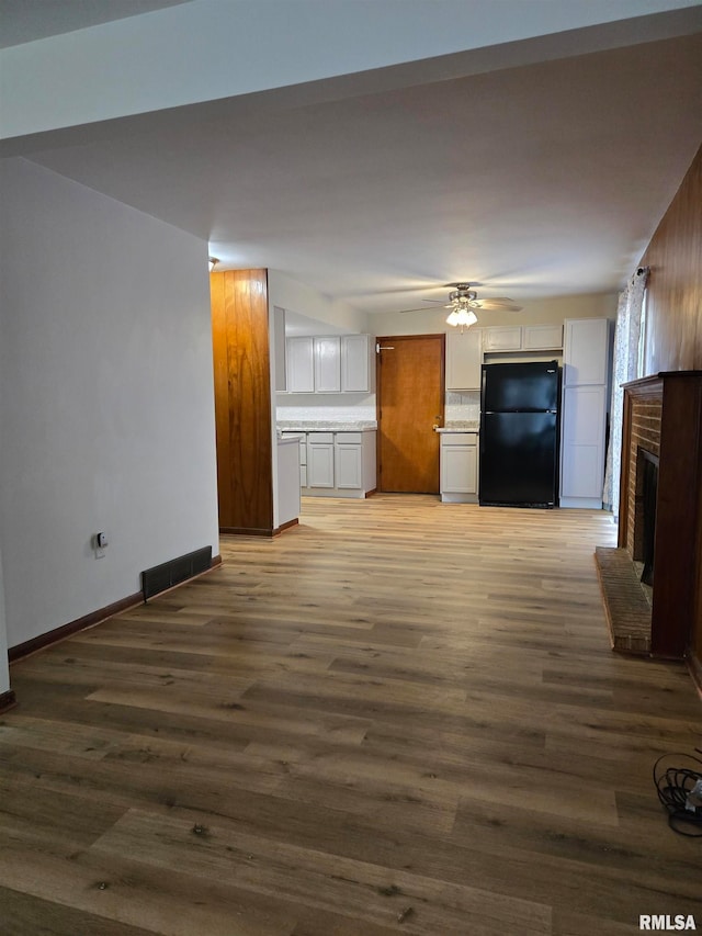 unfurnished living room with ceiling fan, dark hardwood / wood-style floors, and a brick fireplace