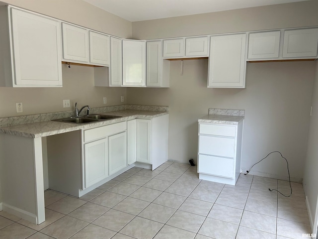 kitchen with white cabinets, sink, and light tile patterned floors