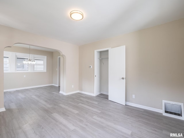 spare room with light hardwood / wood-style flooring and a chandelier