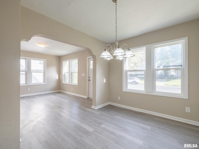 empty room with wood-type flooring and a chandelier