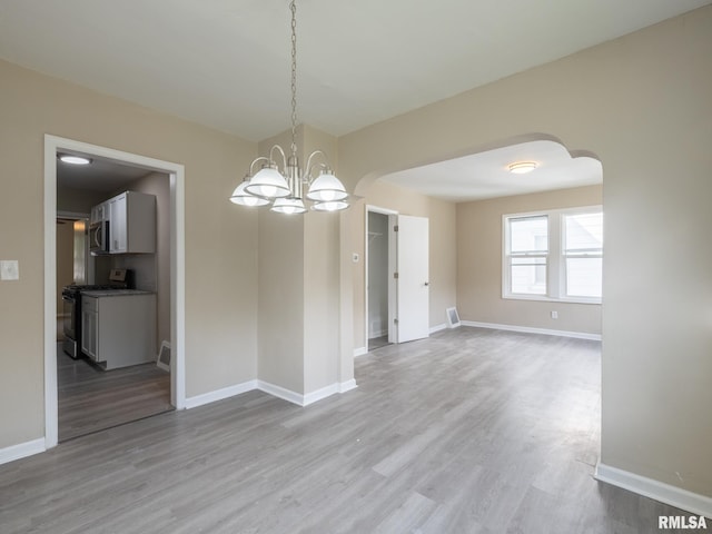 unfurnished dining area featuring light hardwood / wood-style floors and a chandelier