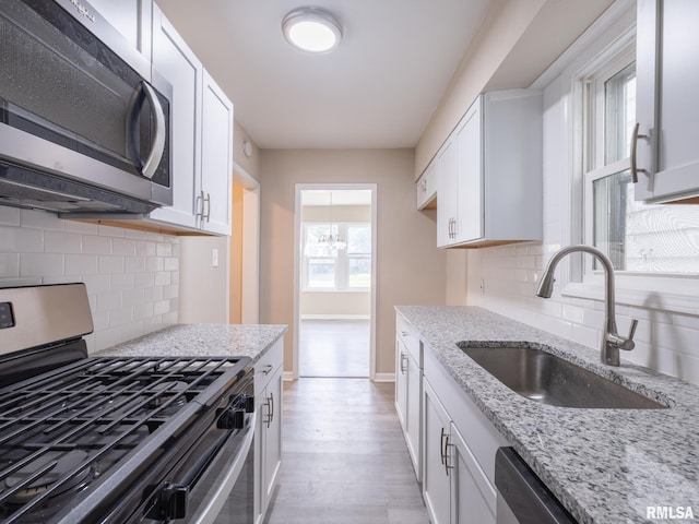 kitchen with backsplash, stainless steel appliances, and white cabinets