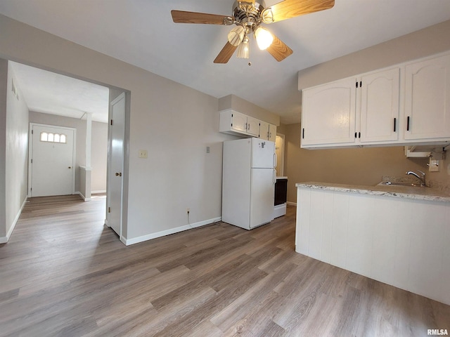 kitchen featuring white cabinetry, white refrigerator, light hardwood / wood-style flooring, ceiling fan, and sink