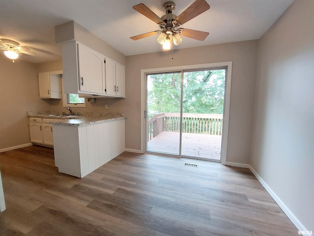 kitchen featuring ceiling fan, light wood-type flooring, sink, white cabinetry, and light stone countertops