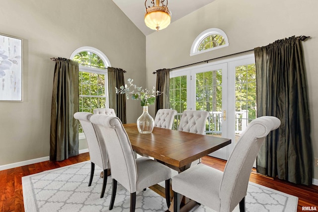 dining space featuring high vaulted ceiling, hardwood / wood-style flooring, plenty of natural light, and french doors