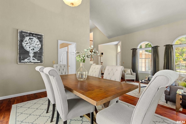 dining area with wood-type flooring and high vaulted ceiling