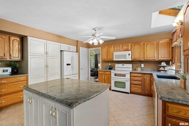 kitchen with light stone counters, white appliances, a kitchen island, ceiling fan, and sink