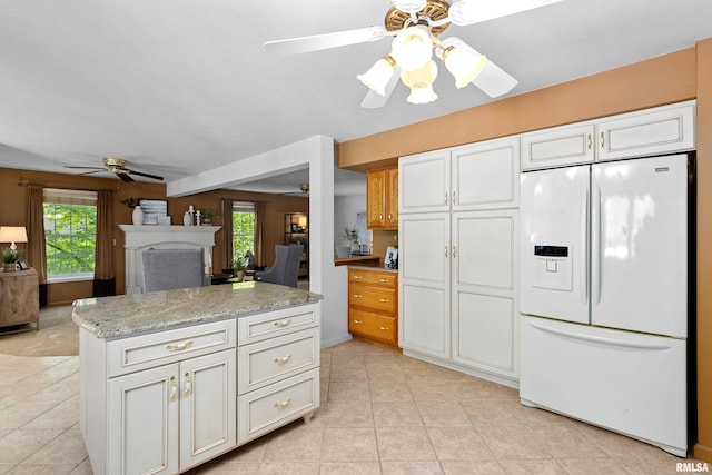 kitchen with white fridge with ice dispenser, ceiling fan, white cabinetry, and a healthy amount of sunlight