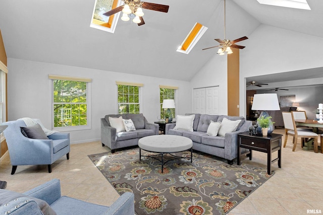 living room with light tile patterned floors, ceiling fan, a skylight, and high vaulted ceiling