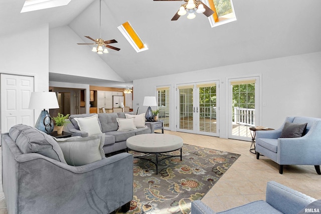 tiled living room with ceiling fan, a skylight, french doors, and high vaulted ceiling