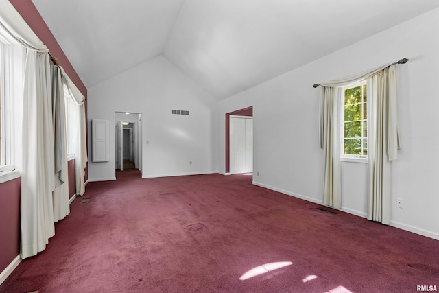 empty room featuring dark colored carpet and high vaulted ceiling