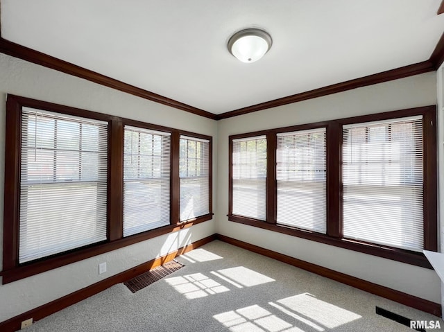 carpeted spare room featuring a healthy amount of sunlight and crown molding