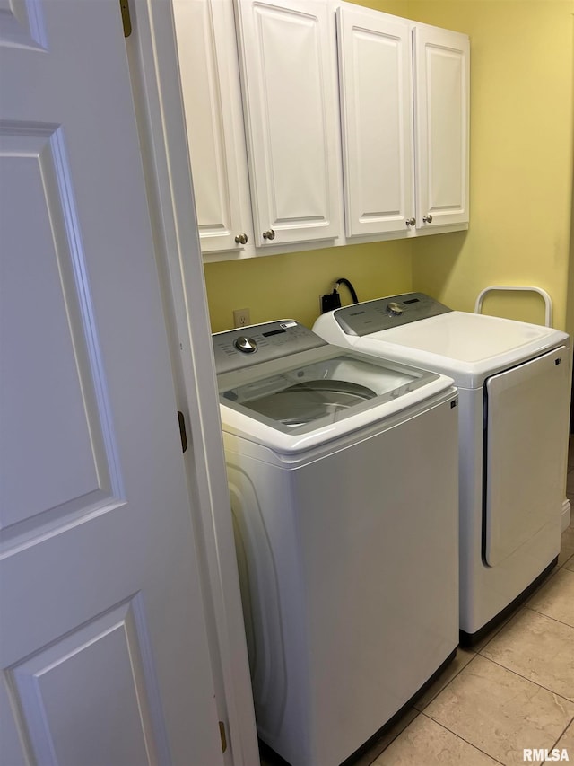 washroom featuring washer and clothes dryer, cabinets, and light tile patterned floors