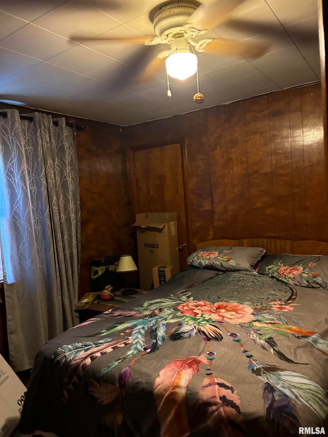 bedroom with wooden walls and ceiling fan