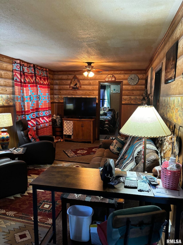 living room with ceiling fan, a textured ceiling, rustic walls, and carpet