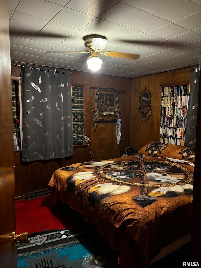 carpeted bedroom with ceiling fan and wood walls