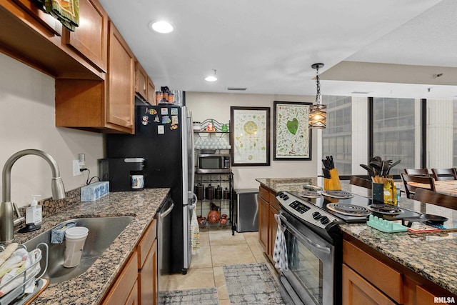 kitchen featuring dark stone countertops, sink, stainless steel appliances, and hanging light fixtures