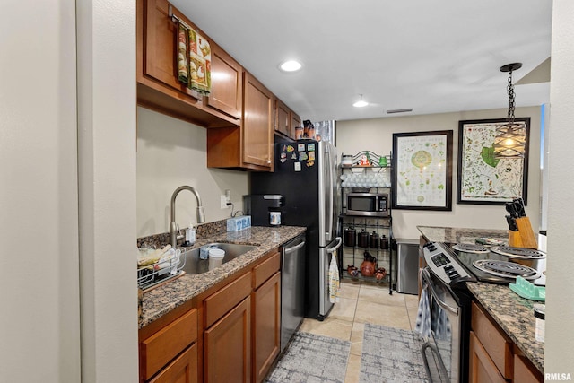 kitchen with hanging light fixtures, sink, dark stone countertops, appliances with stainless steel finishes, and light tile patterned flooring