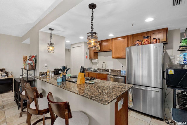 125 SW Jefferson St Unit W-5C, Peoria, IL 61602 - kitchen featuring appliances with stainless steel finishes, brown cabinets, a sink, light tile patterned floors, and a peninsula