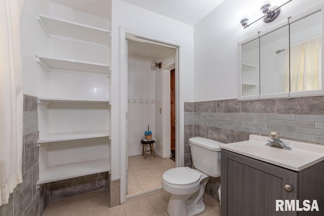 bathroom featuring tile patterned floors, vanity, tile walls, and toilet