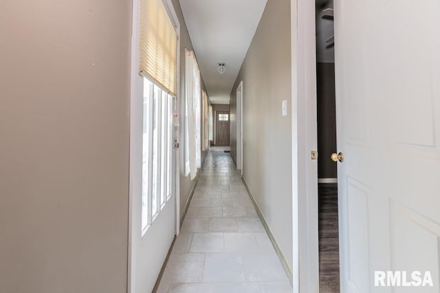 hallway with a healthy amount of sunlight and light tile patterned flooring